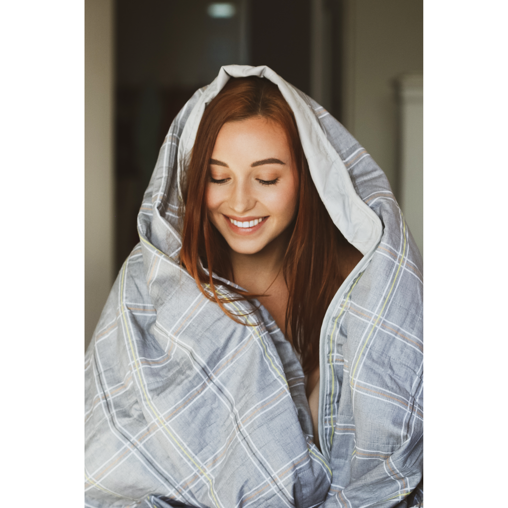 Woman wrapped under a SleepGift 24/7 EMF Protection Blanket.