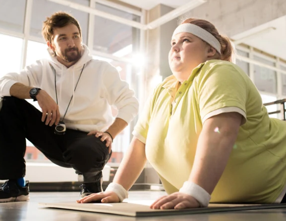 An obese woman trying to lose weight with a trainer on her side, sleep deprivation and its link to body weight and obesity