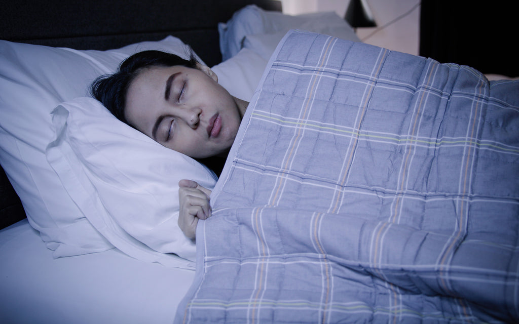 Woman sleeping peacefully on her bed with a SleepGift 24/7 EMF Protection Blanket.