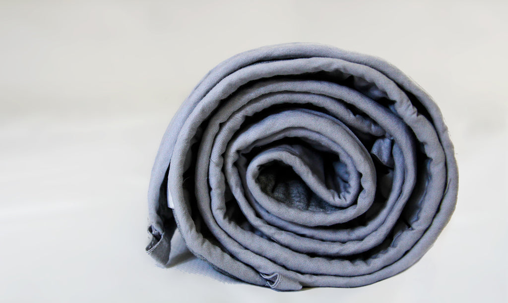 SleepGift Weighted Blanket rolled up on top of a mattress.